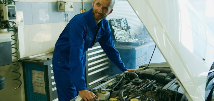 Automehaničar u radnoj odeći i rukavicama u auto-servisu